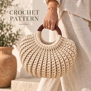 Pode incluir: Uma bolsa de crochê bege com textura arredondada e canelada e uma alça circular de madeira marrom escura. O texto CROCHET PATTERN é visível no canto superior esquerdo. A bolsa tem uma construção tecida espessa com um padrão vertical.