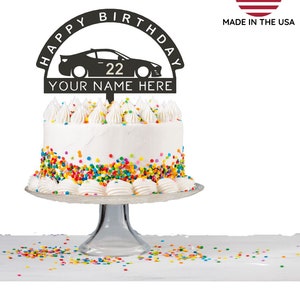 Puede incluir: Topper de pastel de metal negro con las palabras "Happy Birthday" en un semicírculo sobre una silueta de un coche de carreras con el número "22" en el lateral. El texto "Your Name Here" está debajo del coche.