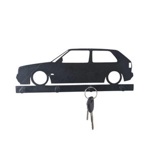 May include: Black metal car-shaped key holder with a horizontal bar for keys. The car silhouette has two doors and two wheels. A set of keys hangs from the key holder.
