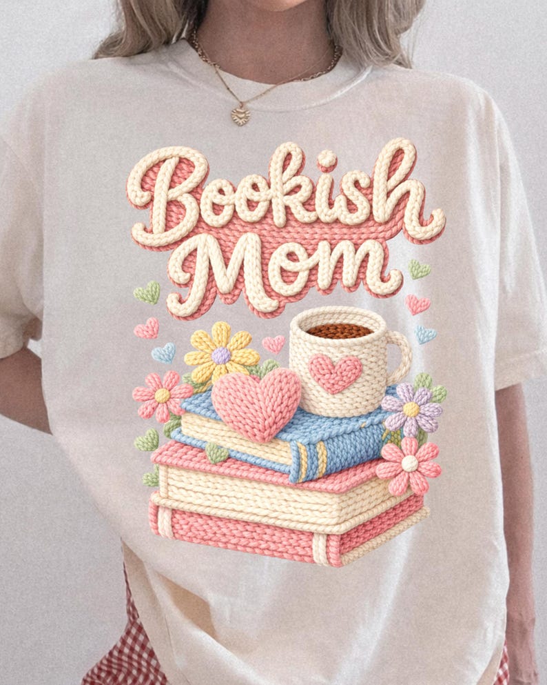May include: Cream-colored t-shirt with the text "Bookish Mom" in a 3D knit design. The graphic includes a stack of books, a coffee mug, flowers, and hearts. The design is in pastel colors.