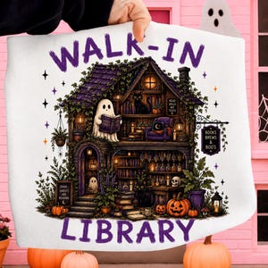 Könnte beinhalten: Ein weißes Sweatshirt mit einer Grafik eines zweistöckigen Hauses und dem Text WALK-IN LIBRARY. Die Illustration zeigt Geister, schwarze Katzen, Kürbisse, Bücherregale und Schilder mit den Aufschriften READ SPELLS NOT TEXTS, SHHH GHOSTS ARE READING und BOOKS BREWS & BOO'S.