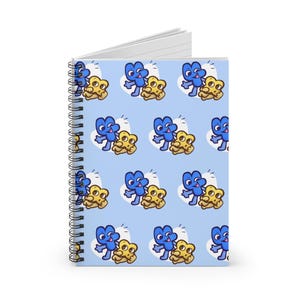 May include: Spiral-bound notebook with a light blue cover featuring a repeating pattern of cartoon characters. The characters are blue and yellow, with white heart-shaped accents. The notebook has a silver spiral binding.