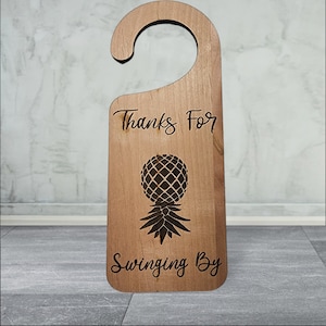 May include: Wooden door hanger with a pineapple design and the text "Thanks for swinging by".