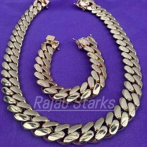 May include: A gold chain necklace and bracelet set with a curb link design. The chain is thick and has a shiny finish.