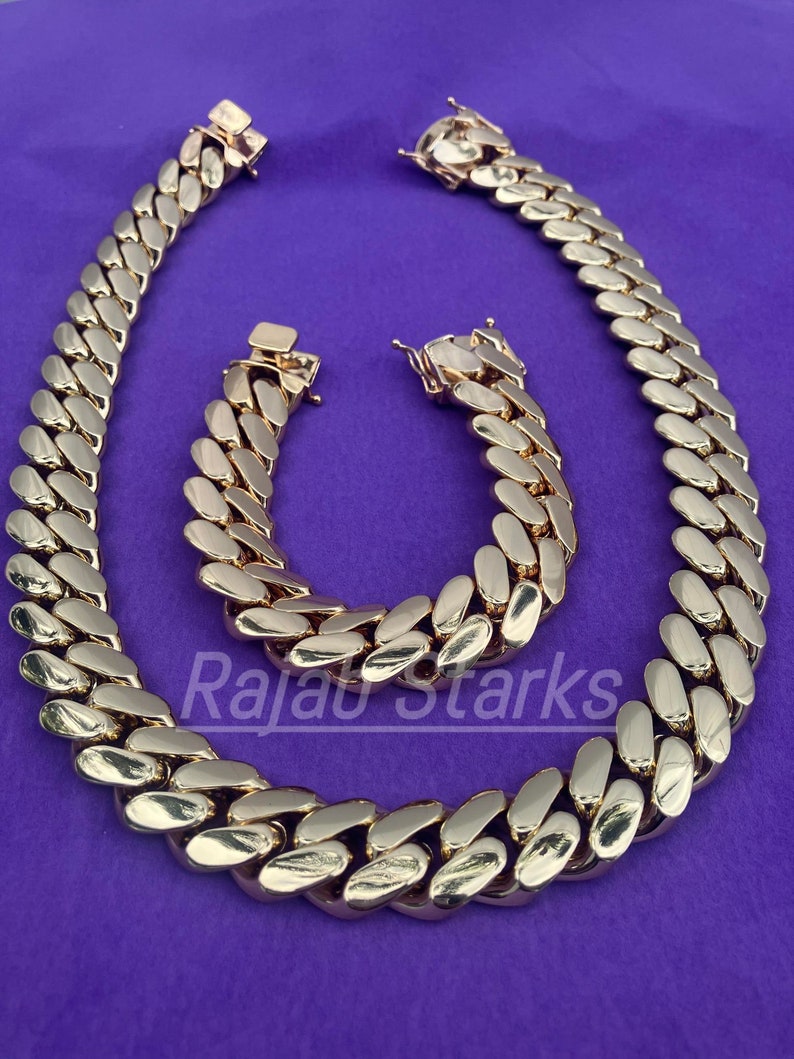 May include: A gold chain necklace and bracelet set with a curb link design. The chain is thick and has a shiny finish.