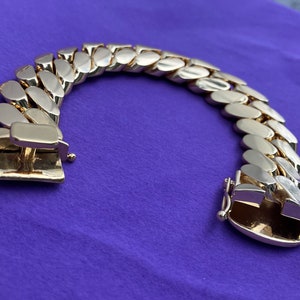 May include: A gold-toned chain bracelet with a curb link design. The bracelet has a clasp closure.