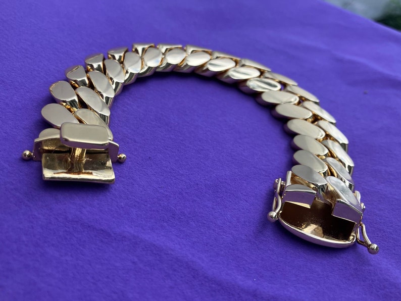 May include: A gold-toned chain bracelet with a curb link design. The bracelet has a clasp closure.