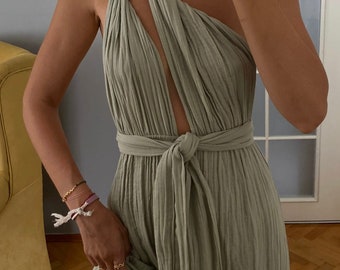 May include: A sage green one-shoulder maxi dress featuring a textured, crinkled fabric, a twisted strap detail at the shoulder, a central cutout, and a matching fabric tie belt at the waist. The dress has a long, flowing skirt with a side slit.