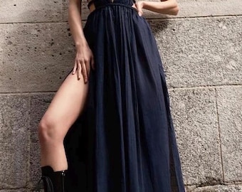 May include: A dark navy blue sleeveless maxi dress featuring a deep V-neckline, a gathered bodice, and a waist section detailed with horizontal corded straps. The skirt includes high side slits, and the garment is paired with black boots.