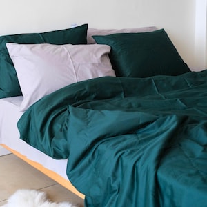 Könnte beinhalten: Ein grüner Bettbezug mit einem weißen und grauen Kissen darauf. Der Bettbezug ist aus einem weichen, glatten Stoff und hat einen dezenten Glanz.