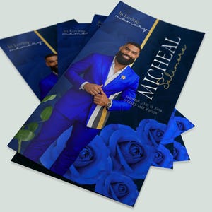 Op de afbeelding: Een stapel herdenkingskaarten met een man in een blauw pak, blauwe rozen en de tekst "Micheal Salimare". De kaarten hebben de tekst "In Loving Memory" en data.
