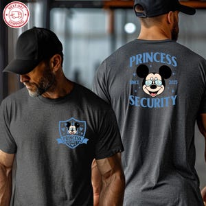 May include: Dark gray t-shirt featuring a cartoon Mickey Mouse wearing glasses, with the text "PRINCESS SECURITY" in light blue. The shirt has a shield design on the front and back, with the text "SINCE 2025".