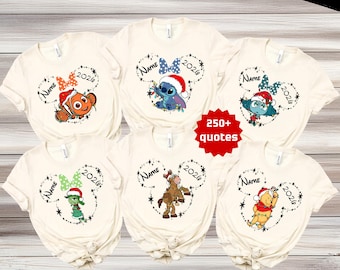 Puede incluir: Seis camisetas de color crema con varios personajes de Disney con ropa navideña, incluidos Nemo, Stitch y Winnie the Pooh. Cada camiseta muestra un personaje dentro de un contorno de orejas de Mickey Mouse con el texto Name y 2026.