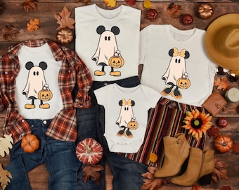 May include: White Halloween-themed t-shirts and a baby onesie featuring a ghost design with Mickey and Minnie Mouse ears, holding a jack-o'-lantern. The shirts are paired with jeans, a plaid shirt, and boots. The text "NEXT DAY SHIPPING" is at the top.