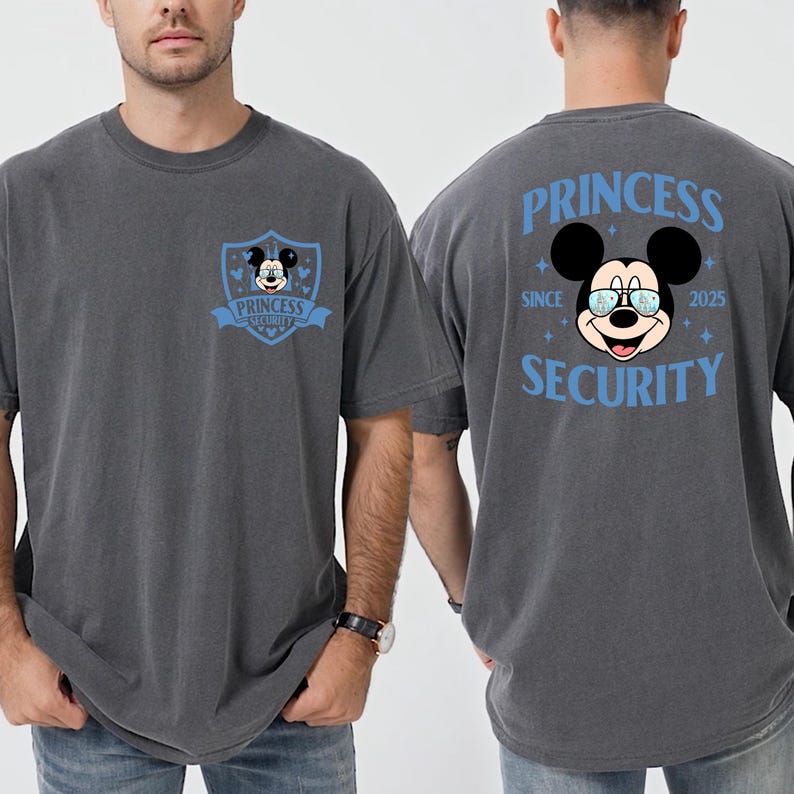 May include: Gray t-shirt featuring a Mickey Mouse graphic with the text "PRINCESS SECURITY" in blue. The front of the shirt has a shield design with Mickey Mouse. The back of the shirt has a larger Mickey Mouse graphic with the text "PRINCESS SECURITY SINCE 2025".