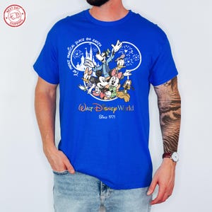 Puede incluir: Camiseta azul real con un dise&ntilde;o de personajes de Disney, incluyendo Mickey Mouse, Minnie Mouse, Donald Duck y Goofy. El dise&ntilde;o incluye el texto "The Most Magical Place on Earth" y "Walt Disney World Since 1971".