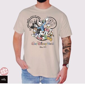 Puede incluir: Camiseta beige con un gr&aacute;fico colorido de personajes de Disney, incluyendo Mickey Mouse, Minnie Mouse y el Pato Donald. El dise&ntilde;o incluye el texto "Walt Disney World Since 1971" y "The Most Magical Place on Earth."