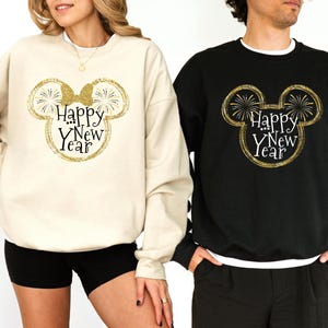 Pu&ograve; includere: Due felpe, una color crema e una nera, ciascuna con un design a testa di topo glitterato dorato, fuochi d'artificio e la scritta "Happy New Year". La felpa color crema ha girocollo e maniche lunghe. La felpa nera ha girocollo bianco e maniche lunghe.