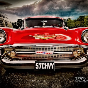 May include: A classic red 1957 Chevrolet Bel Air with chrome accents and a gold grille. The car has a license plate that reads "57CHVY".