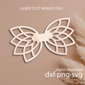 May include: A laser-cut wooden wing file with a symmetrical design and floral patterns. The text "LASER CUT WINGS FILE" is at the top, and "digital download dxf.png.svg" is at the bottom. The copyright information is also included.