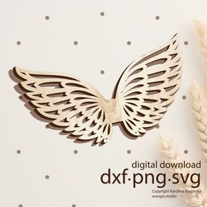 May include: Wooden cutout of a pair of angel wings with a detailed, intricate design. The wings are light brown and have a 3D effect. The image includes the text "digital download dxf.png.svg Copyright Karolina Nagorska woogie.studio".