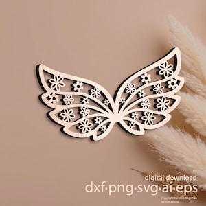 May include: A wooden wing-shaped decoration with a floral design. The wing is light-colored with a dark outline and features numerous small flower cutouts. The background is a neutral tan color. The text "digital download dxf.png.svg.ai.eps" is visible.