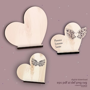 Puede incluir: Tres decoraciones de madera en forma de corazón. Dos tienen un diseño de alas decorativas, y una tiene el texto "Pierusza Komunia Swieta". Los corazones son de madera clara con bases negras. Descarga digital disponible.