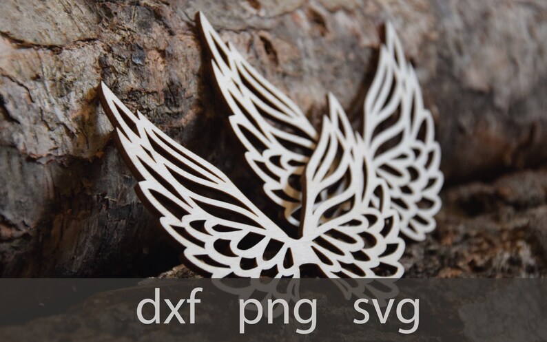 May include: Two intricately cut wooden wings with a delicate, lacy design. The wings are light brown and have a natural wood finish. They are arranged in a symmetrical pattern, with the tips of the wings pointing upwards.