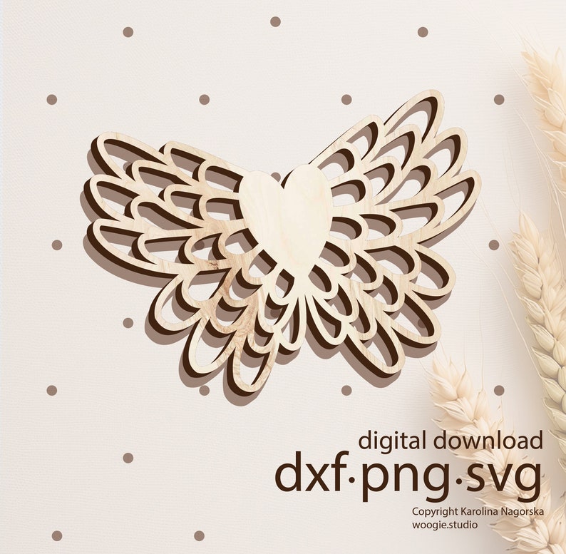 May include: A wooden cutout of a heart with wings. The wings are made of overlapping circles, creating a delicate and intricate design. The heart is in the center of the wings and is slightly raised.