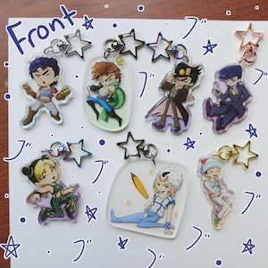 Puede incluir: Siete llaveros de acrílico con personajes de estilo anime y cierres en forma de estrella. Los personajes aparecen en varias poses, algunos con accesorios como una tabla de surf. La palabra Front y caracteres japoneses están escritos en tinta azul.