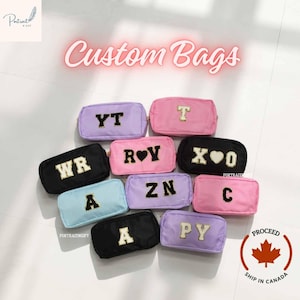 Peut inclure: Une collection de trousses rectangulaires à fermeture éclair dans diverses couleurs, notamment noir, bleu clair, lavande et rose. Chaque trousse présente de grandes lettres pailletées à bordure dorée ou des cœurs sur le devant.