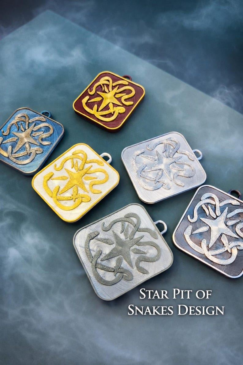 Puede incluir: Conjunto de colgantes cuadrados con dise&ntilde;o de estrella y serpiente. Los colgantes est&aacute;n disponibles en varios colores, como azul, dorado, plateado y burdeos. Se puede leer el texto "STAR PIT OF SNAKES DESIGN". Cada colgante tiene un peque&ntilde;o lazo.