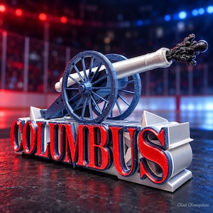 Op de afbeelding: Een decoratief kanonmodel met een zilveren loop, een zwart rookeffect bij de monding en blauwe wielen. Het kanon rust op een zilveren voetstuk met het woord COLUMBUS in dikke rode letters met blauwe omlijningen.