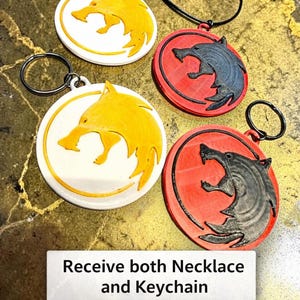 Puede incluir: Juego de collar y llavero con dise&ntilde;o de lobo. Los colgantes son circulares con una silueta de lobo. Un juego tiene un lobo amarillo sobre fondo blanco, el otro tiene un lobo negro sobre fondo rojo. El texto dice "Recibe tanto el collar como el llavero".