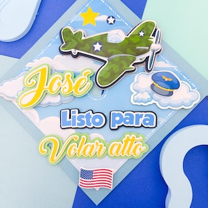 Puede incluir: Manualidad de papel en capas con un avión verde camuflaje, un gorro de piloto y el nombre "Jose" en escritura amarilla. El texto "Listo para Volar alto" está presente, junto con una bandera americana y estrellas, sobre un fondo de cielo azul.