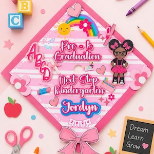 Puede incluir: Un gorro de graduación rosa decorado con las palabras "Pre-K Graduation" y "Next Stop Kindergarten Jordyn 2026." El gorro presenta un arcoíris, un sol sonriente y una niña de dibujos animados. Decoraciones adicionales: bloques ABC, crayones y un lazo.