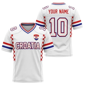 May include: White Croatia football jersey with red and blue detailing. The jersey displays the word "CROATIA" across the chest and the number "10" on the back. It also has a Croatian coat of arms patch.