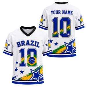 Op de afbeelding: Een wit shirt met V-hals voorzien van de tekst BRAZIL en het nummer 10 op de voorzijde, en de tekst YOUR NAME met het nummer 10 op de achterzijde. Het ontwerp bevat blauwe en gele sterren, groene en gele penseelstreken en een Braziliaanse vlag.