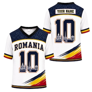 May include: A white V-neck jersey featuring the text ROMANIA and the number 10 with a city skyline graphic. The shoulders have a dark blue patterned yoke, and the bottom features diagonal stripes in blue, yellow, and red. The back displays YOUR NAME.