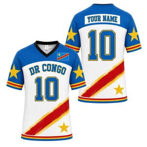 May include: A white and blue V-neck jersey featuring the text DR CONGO and the number 10 on the front, with the text YOUR NAME and the number 10 on the back. The design includes yellow stars, a diagonal red and yellow stripe, and the DR Congo flag.