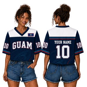 Könnte beinhalten: Ein marineblau-weißes Trikot mit V-Ausschnitt, das vorne den Schriftzug GUAM und hinten YOUR NAME mit der Nummer 10 zeigt. Die Ärmel tragen die Nummer 10, und auf der Vorderseite befinden sich ein kleines Guam-Flaggenemblem und dezente Kreismuster.