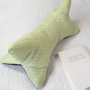 May include: A lime green and white patterned pillow with a black backing. The pillow is shaped like a wedge and is designed to be used for reading or watching TV in bed.