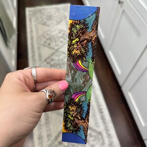 May include: A colorful bookmark with a psychedelic design featuring a tree, rainbows, and swirling patterns.