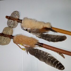 May include: Two Native American style peace pipes with stone heads and brown leather wrapped handles. Each pipe is adorned with feathers and beads.