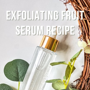 May include: A clear glass bottle with a gold cap filled with a clear liquid. The bottle is labeled "EXFOLIATING FRUIT SERUM RECIPE". The bottle is surrounded by green leaves and a brown woven wreath.