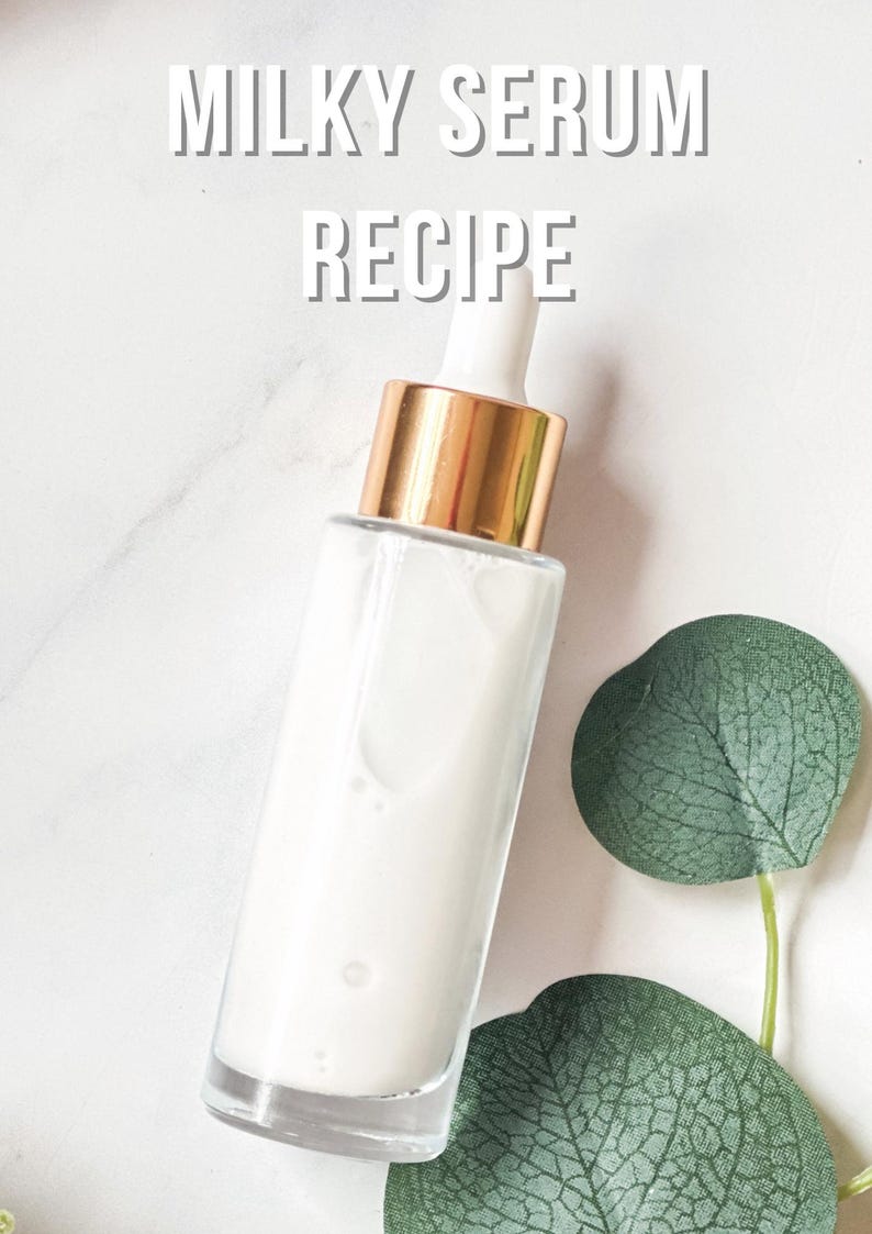 May include: A clear glass bottle filled with a milky white liquid, topped with a gold and white dropper. The words "MILKY SERUM RECIPE" are printed in white. A green leaf is next to the bottle on a white marble surface.
