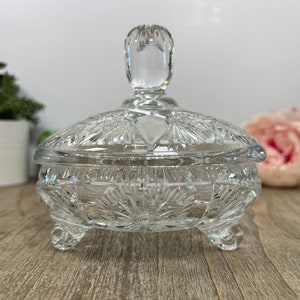 Puede incluir: Un platito de cristal transparente para dulces con tapa. El plato tiene un dise&ntilde;o de cristal tallado y se apoya en tres patas. La tapa tiene un pomo en la parte superior.