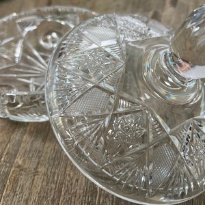 Puede incluir: Un plato de vidrio transparente con tapa, decorado con un dise&ntilde;o de vidrio cortado. La tapa tiene un pomo en la parte superior.