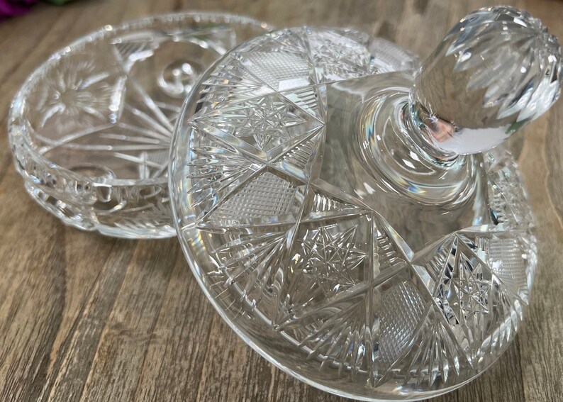 Puede incluir: Un plato de vidrio transparente con tapa, decorado con un dise&ntilde;o de vidrio cortado. La tapa tiene un pomo en la parte superior.