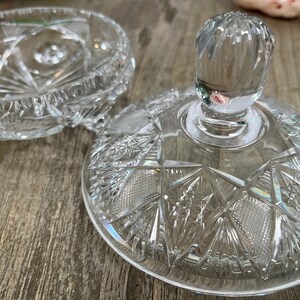 Puede incluir: Un plato de vidrio transparente con tapa, decorado con un dise&ntilde;o de vidrio cortado. La tapa tiene un pomo en la parte superior.